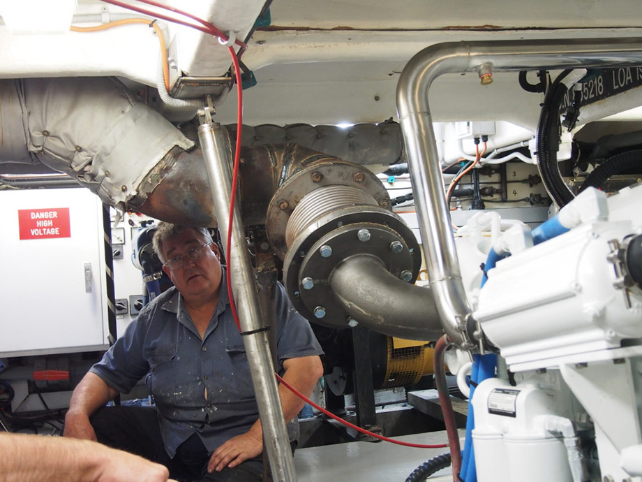 New main engine installed in commercial fishing vessel in Moolloolaba Qld. Owner sitting under exhaust adaption from new engine exhaust riser to original exhaust.